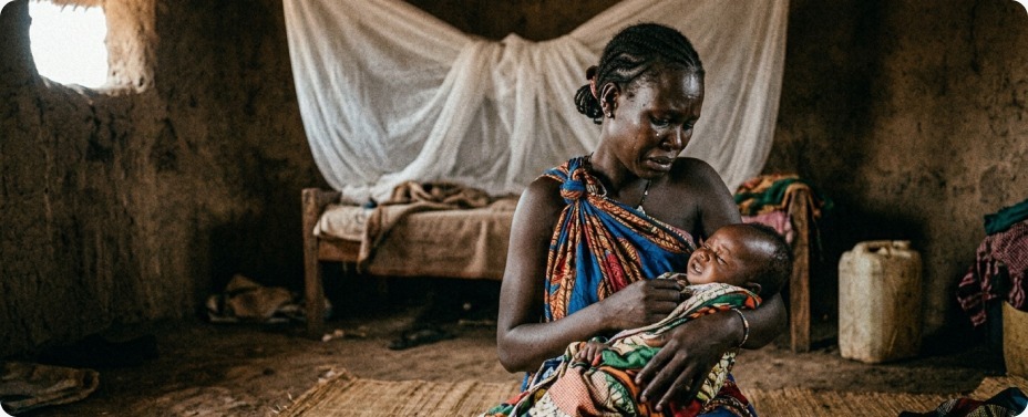 A concerned African mother holding her crying baby with a suspected mosquito bite, highlighting the urgent need for World Malaria Day 2026 impact Africa initiatives.