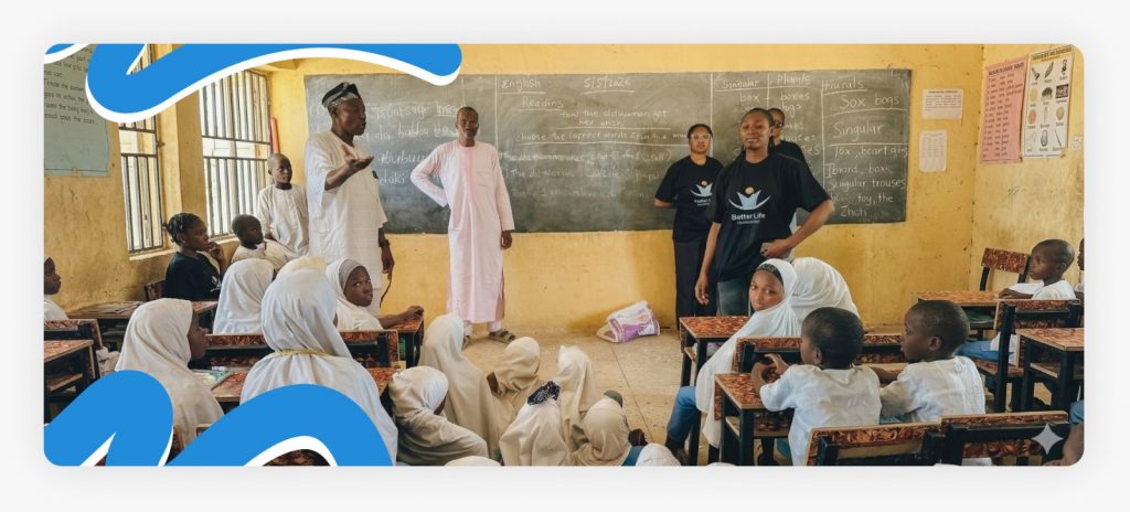 Better Life NGO outreach representatives and two teachers standing alongside happy students inside a classroom funded by charitable donations for schools in Africa.