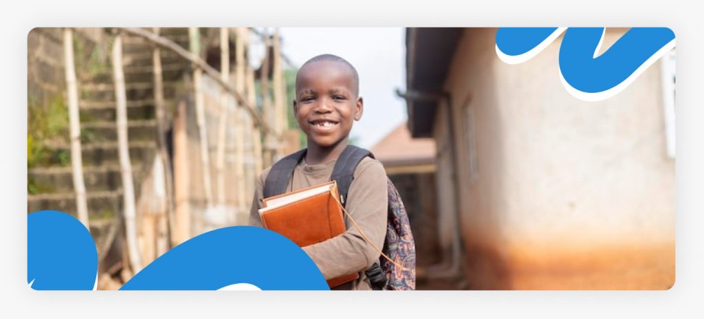 A smiling little boy in a rural community holding a school book and wearing a backpack, symbolizing the successful recovery of children from substance abuse through education and donor support in 2026.