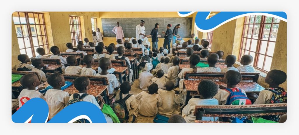 Primary school children sitting on the floor and a few sharing chairs due to the severe desk crisis and lack of primary school support in Africa.
