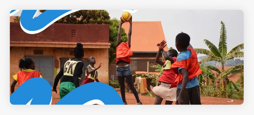 A group of young African boys with serious, determined expressions chasing a football on a rugged dirt ground, showing the raw passion that drives our support for youth sports in Africa.