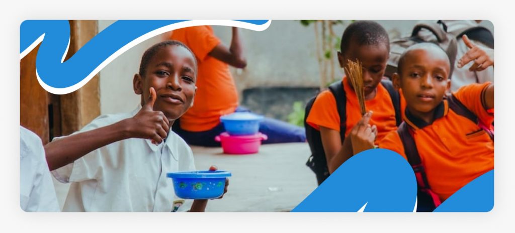 A happy young boy giving a thumbs up while holding a full plate of food, demonstrating the life-saving impact of food vouchers for malnourished children in Africa in 2026.