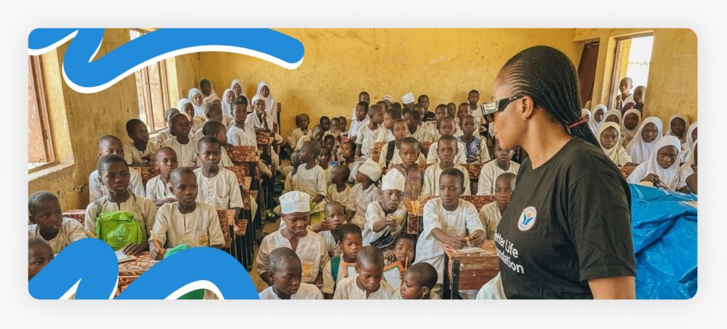 Primary school kids sitting and listening intently as Better Life NGO staff address the classroom, proving how impactful education can be in Africa when communities are supported.
