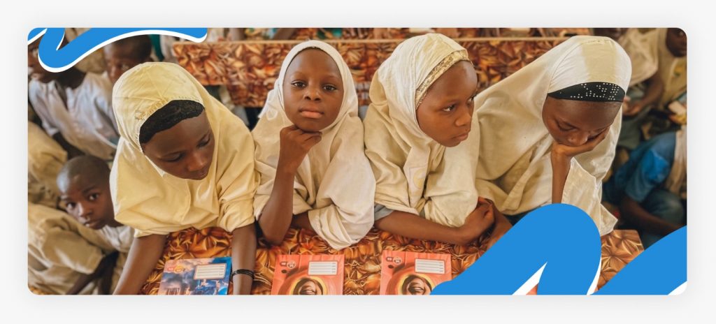 Primary school children holding their new exercise books in class, demonstrating the direct impact of our efforts giving back to the community.