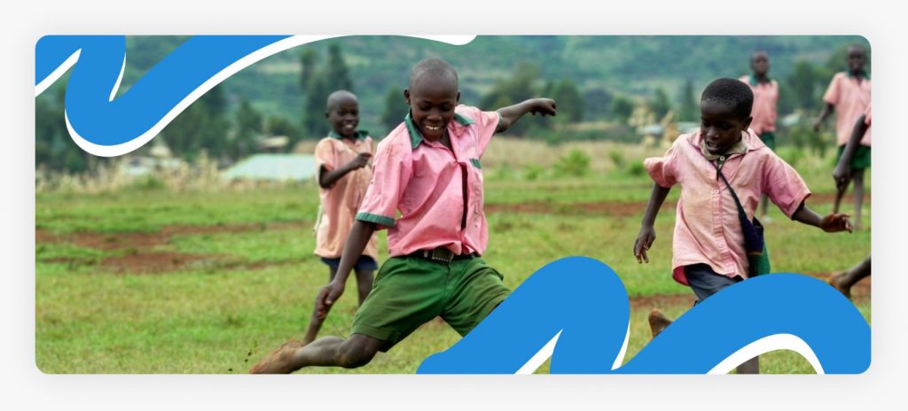 School children happily playing football together in the open yard of a rural community primary school, demonstrating the active integration of sports education for rural boys in Africa