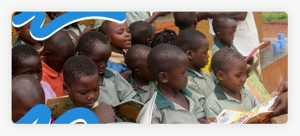 Primary school children standing and proudly holding their new textbooks while learning in Africa’s underserved communities.