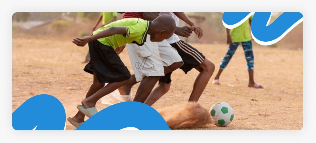 A group of children playing seriously on a rural African field, demonstrating the resilience and social development gained through community sports in 2026.