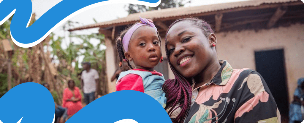 A smiling African mother standing and holding her child, demonstrating the positive impact of providing support for suffering mothers in Africa.