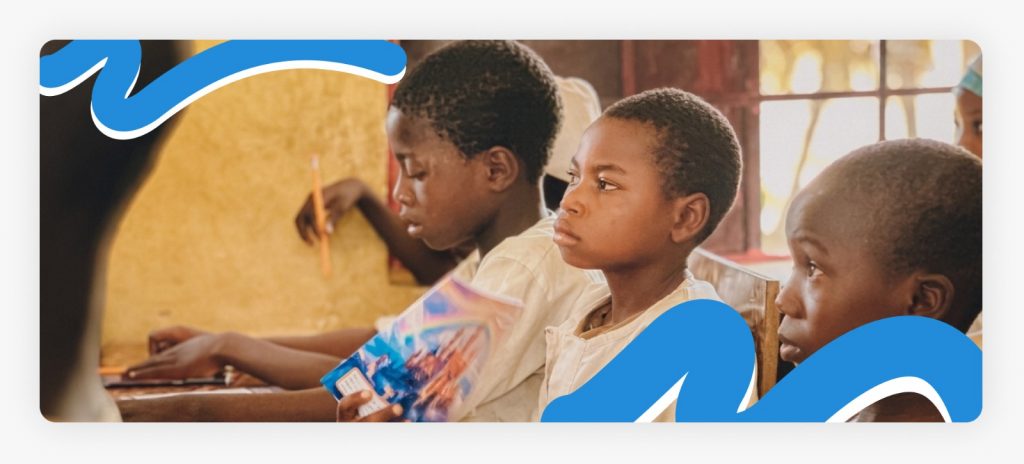Primary school students holding up their new books and pencils from the educational equipment for students in Africa distribution by Better Life NGO.