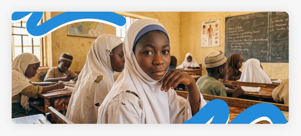 Two young schoolgirls sitting together in class with noticeably torn uniforms, emphasizing why our campaign is so urgent since most children had worn thorn uniforms to school.