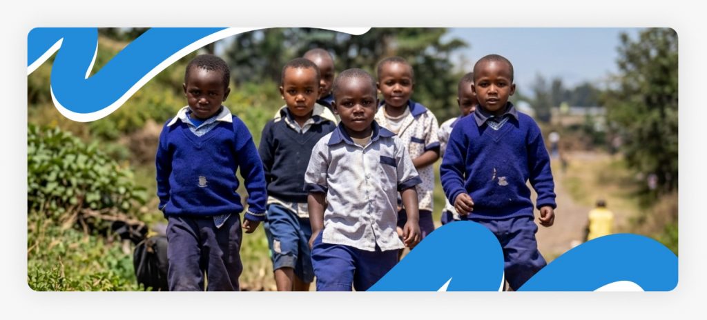Young African school children trekking together on their long morning walk heading to school in a remote, underserved village.